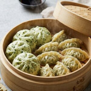 Bamboo steamer filled with kale-flecked vegetarian steamed buns and pleated dumplings, garnished with fresh kale leaves and sliced bamboo shoots, illustrating the new formats bringing vegetarian variety to international frozen retail.